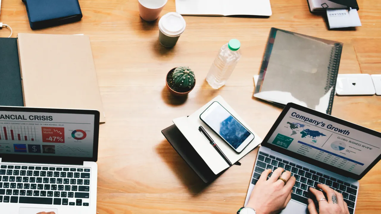 Overhead view of a B2B marketing team around a meeting table with laptops showing growth and performance charts, comparing options while choosing the best SEO agency for B2B